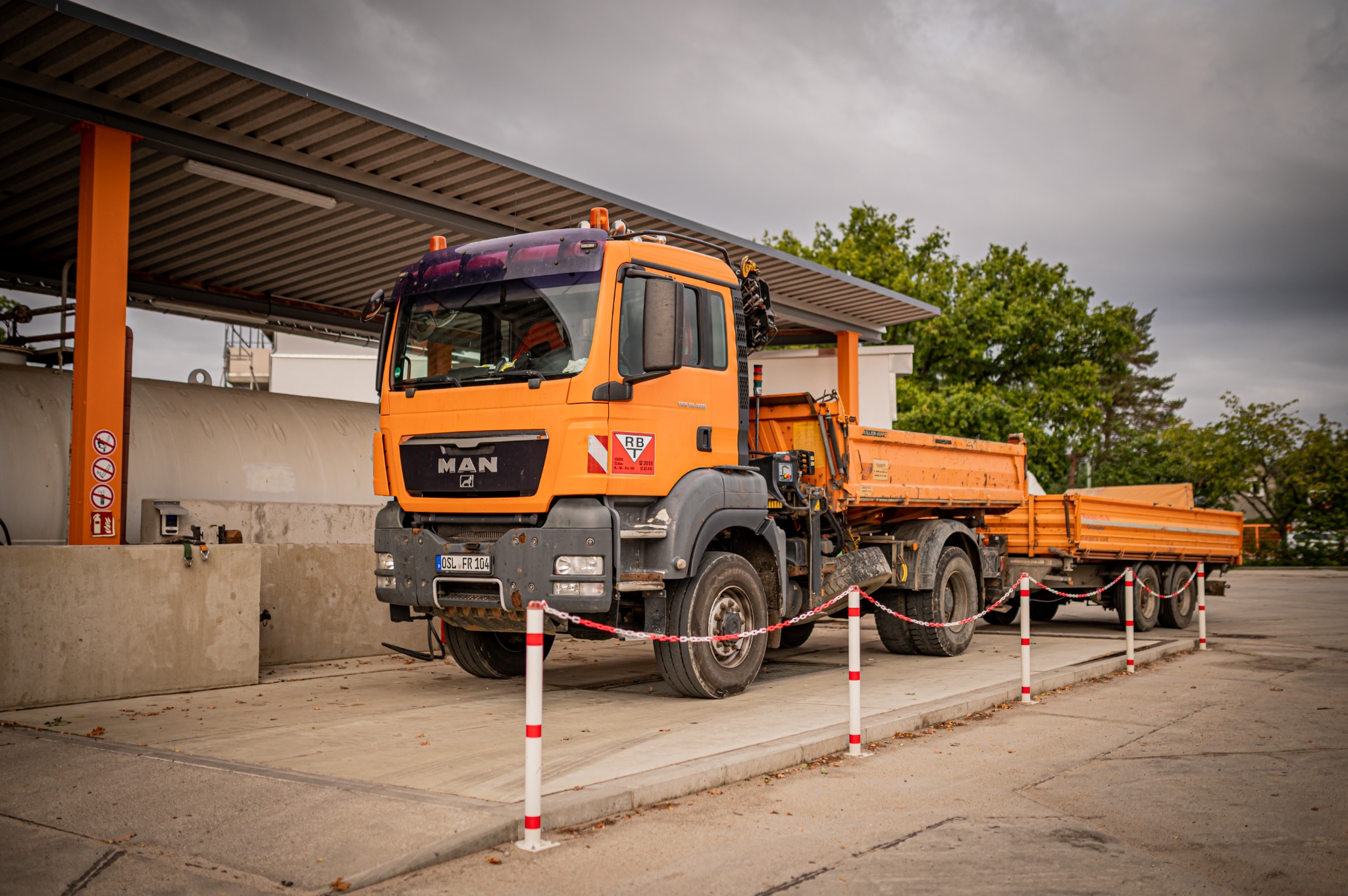 Orangefarbener RBT-MAN-Lkw mit Anhänger auf dem Betriebshof