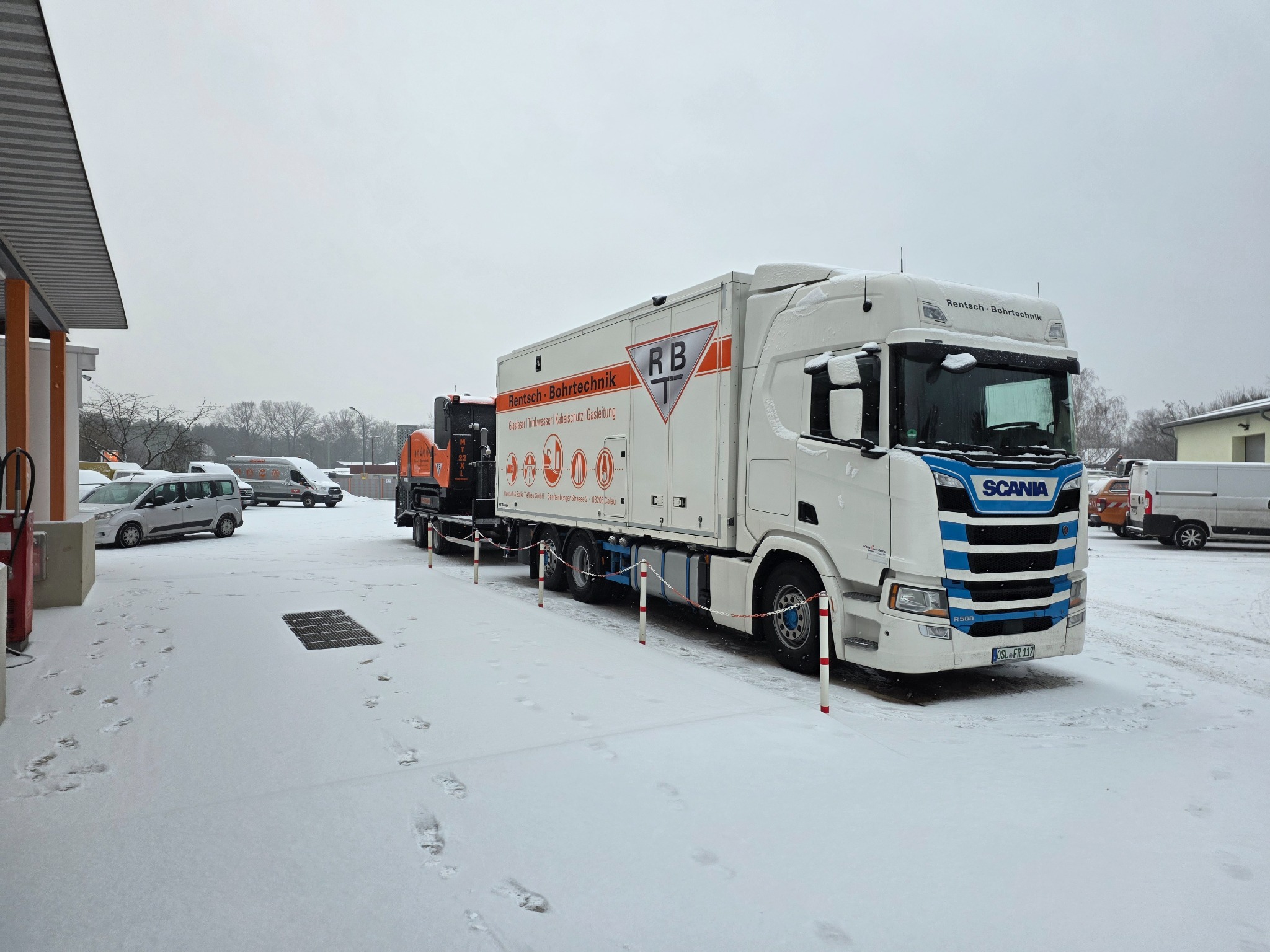 Weiß-blauer RBT-Scania-Lkw mit Bohrtechnik auf dem verschneiten Betriebshof
