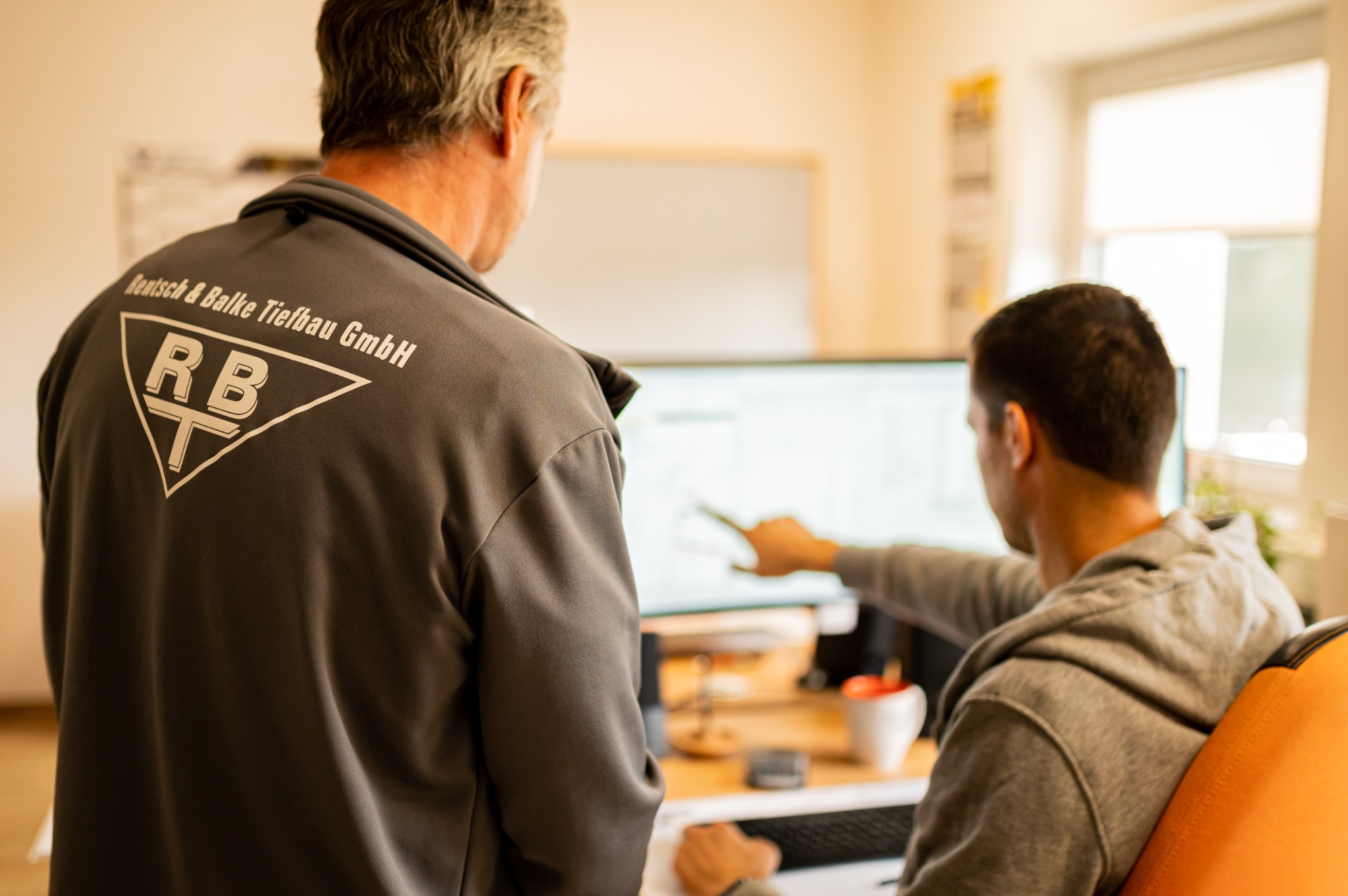 Zwei RBT-Mitarbeiter besprechen gemeinsam die Planung am Bildschirm