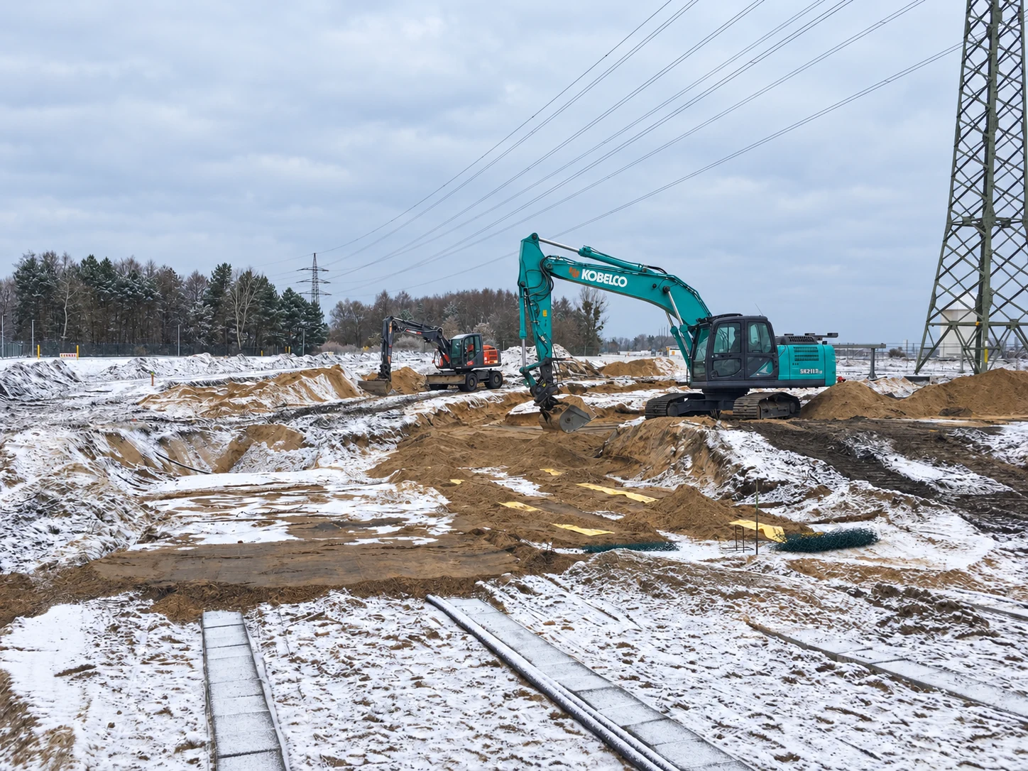 Großer Kettenbagger und Mobilbagger auf einer winterlichen Baustelle